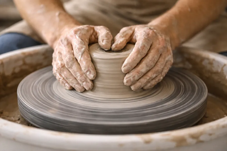 Mains d'un potier centrant l'argile sur un tour de potier