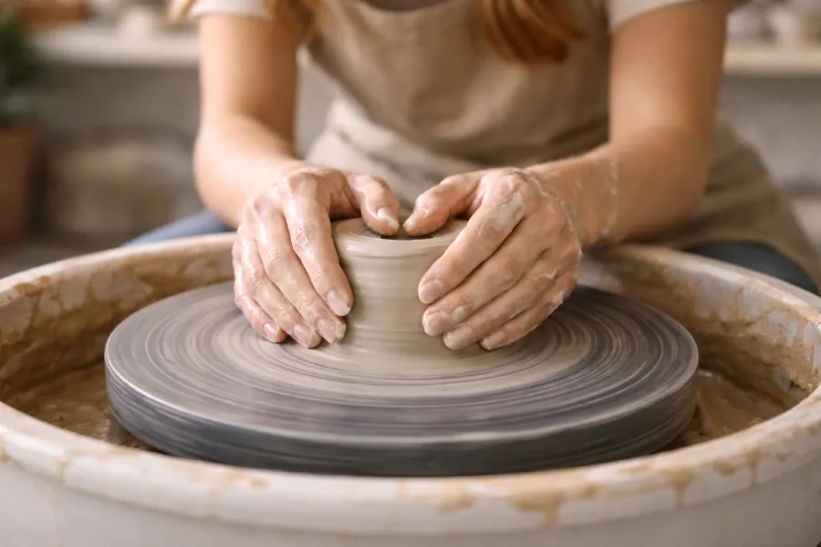 Main de potière travaillant l'argile sur un tour professionnel